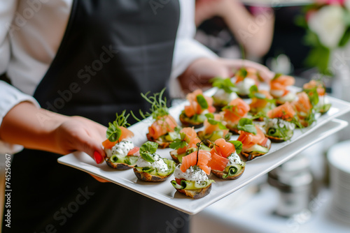 Elegant party appetizers: seafood and cheese canapes on a waiter's tray.