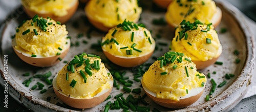 A plate of deviled eggs topped with fresh chives, presenting a delicious and visually appealing appetizer option. The eggs are filled with a creamy and flavorful mixture and garnished with finely