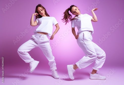 Two Girls Engaging in a Synced Dance Routine Against a Pink Backdrop