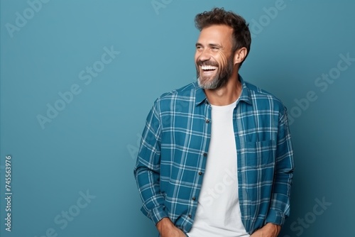 Portrait of a handsome mature man smiling while standing against blue background