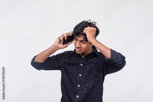 Young Indian man in a black shirt looking agitated while having a heated phone conversation, possibly with his girlfriend.