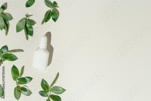 Seasonal spring allergies, fresh spring blooming branches tree with green new leaves and mock up white nasal spray bottle, beige background, top view trend pattern, Seasonal allergy concept