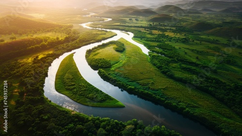 Aerial view of a meandering river through vibrant green wetlands at sunset
