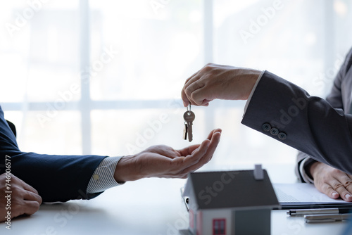 Real estate agent handing over house keys to client. Home ownership and real estate transaction concept.