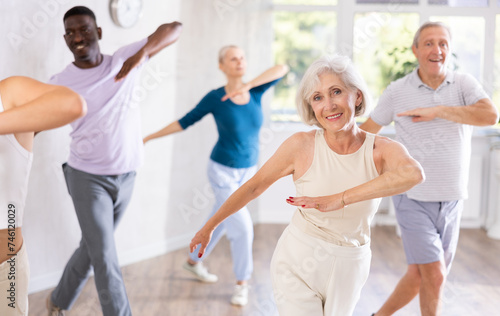 Enthusiastic elderly woman practicing modern vigorous dance movements in group dance class for adults