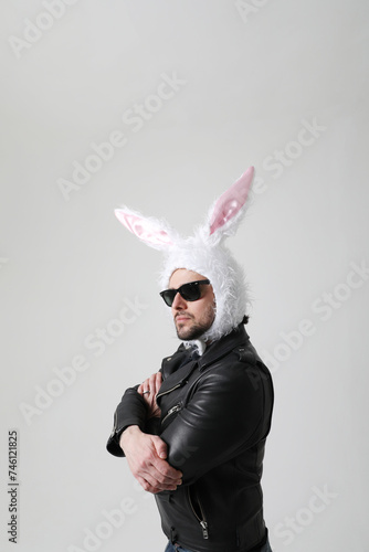 Portrait of bearded man wearing bunny ears and sunglasses posing indoor. 