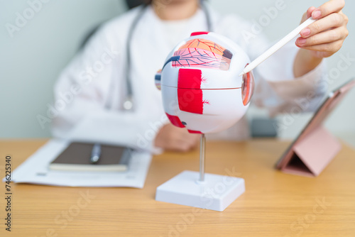 Doctor with human Eye anatomy model with magnifying glass. Eye disease, Refractive Errors, Age Related Macular Degeneration, Cataract, Diabetic Retinopathy, Glaucoma, Amblyopia, Strabismus and Health