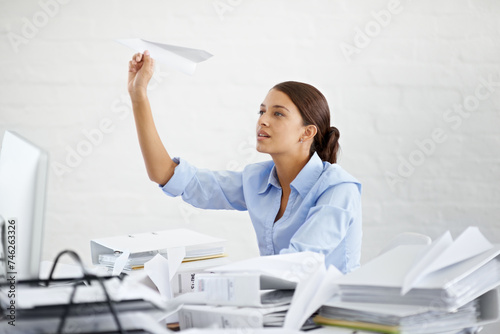 Corporate, businesswoman and paper plane at desk, sitting and thinking while working. Employee and paperwork with files in professional workspace, procrastination and avoid with distraction game