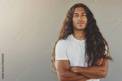 A man with flowing long hair crossed arms and a relaxed stance.