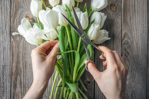 A florist girl makes a bouquet of tulips flowers, cuts the ends with shears.