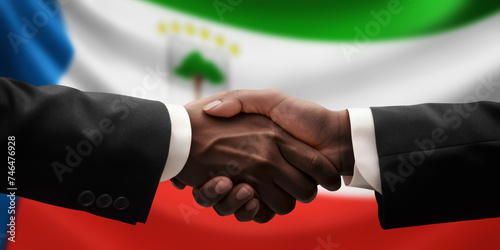 Businessman, diplomat in suits clasp hands for handshake over Equatorial Guinea flag, agree on united success in trade, diplomacy, cooperation, negotiation, teamwork in commerce, gesture of greeting