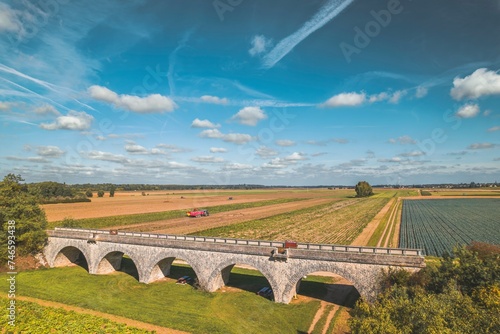 A breathtaking aerial perspective captures a majestic bridge as it spans over a vast field, connecting two distant ends in a harmonious blend of engineering and nature