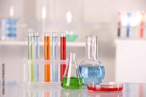Laboratory analysis. Different glassware with liquids on white table against blurred background. Space for text