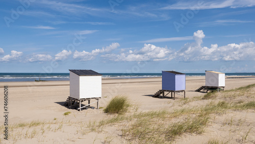 Kleine Strandhäuser am menschenleeren Strand mit Meer und Himmel im Hintergrund