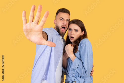 Frightened young european couple gesturing stop to camera