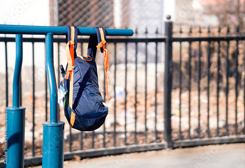 A book bag hanging from the parallel bars equipment