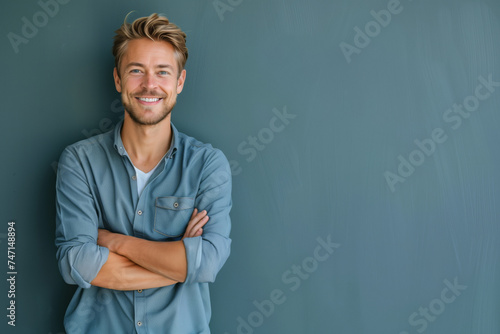Confident Young Man with Arms Crossed Wearing a Casual Buttoned Shirt on a Smooth Blue Background