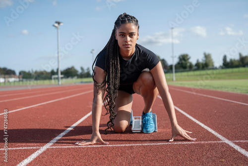 Female athlete preparing to run at stadium