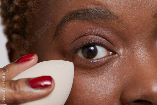 Close-up of woman applying make up foundation with sponge