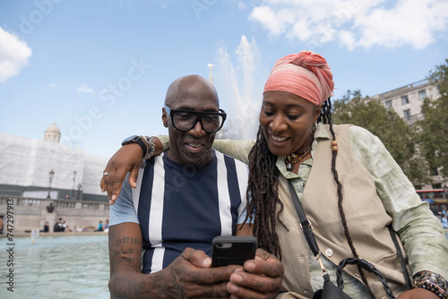 UK, London, Happy mature couple posing next to fountain in Trafalgar Square