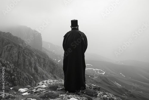 russian orthodox monk standing in mountains from his back in mountains