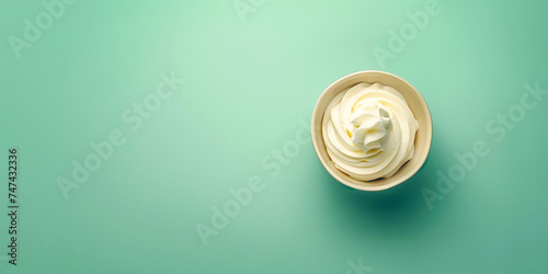 Creamy cream in a cup on a green background, top view