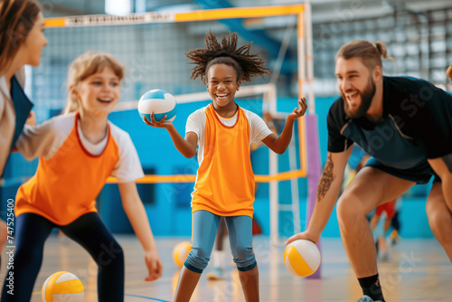 Happy Kids Play Ball Sports With Young Coach. School Children Have Fun and Play Ball Sports. Happy Female Sports Team Throwing Balls on Sports Court