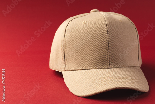 A beige baseball cap is positioned against a red background, with copy space