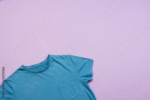 A blue t-shirt is laid out on a purple background, with copy space