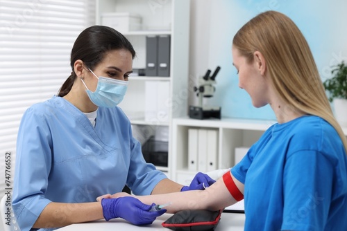 Laboratory testing. Doctor taking blood sample from patient at white table in hospital