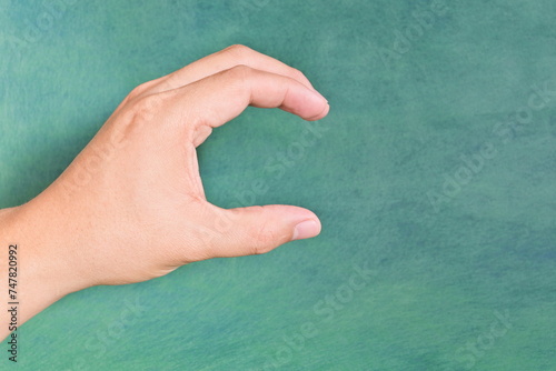 Young male Asian hand making letter C sign isolated on green background.