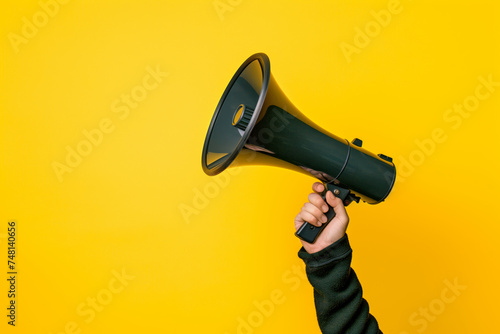 A hand firmly grips a black and green megaphone, ready to amplify sound. The contrast between the dark megaphone and the vibrant green accents creates a striking visual.
