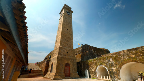 Ancient clock tower in fortress. Action. Beautiful sunny view of stone walls and clock tower in ancient fortress. Ancient fortress with clock tower on sunny summer day