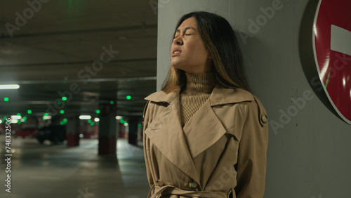 Frightened Asian ethnic chinese korean woman hiding from danger pursuit threat phobia in underground shelter night dark car parking scared fearful girl stand alone near stop driving traffic road sign