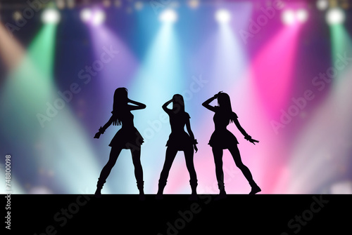 ステージ上の3人の女性アイドルとカラフルなスポットライト