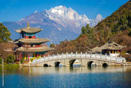 Bridge and pagoda pavilion at the Black Dragon Pool with Yulong Snow Mountain in the background. Lijiang, Yunnan, China