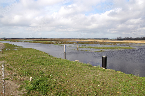 Polder water storage at very high rain water. Partially flooded to protect the low polders in the neighbourhood. Near the Dutch village of Bergen. Ditch, meadows, clouds. Netherlands, March 1. 