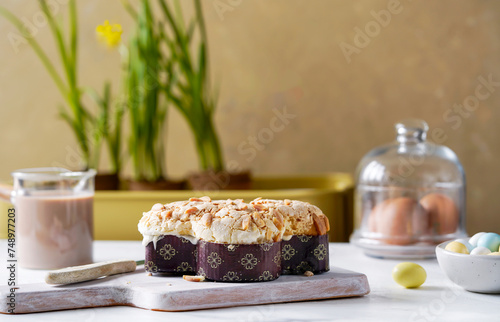 Traditional Italian Easter bread colomba topped with sliced almonds and icing, served with a side of chocolate eggs and fresh spring daffodils