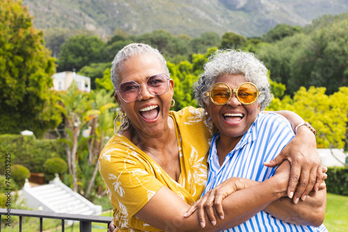 Senior African American woman and senior biracial woman share a joyful embrace outdoors