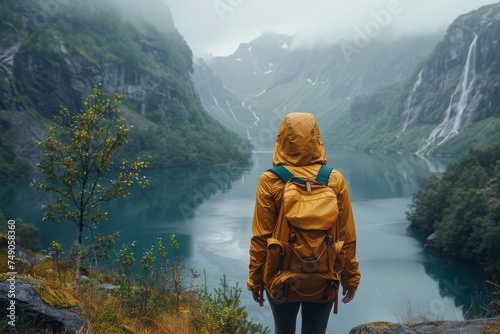 An adventurous soul stares out at a foggy, mountain-fringed lake, capturing the mystery and grandeur of nature