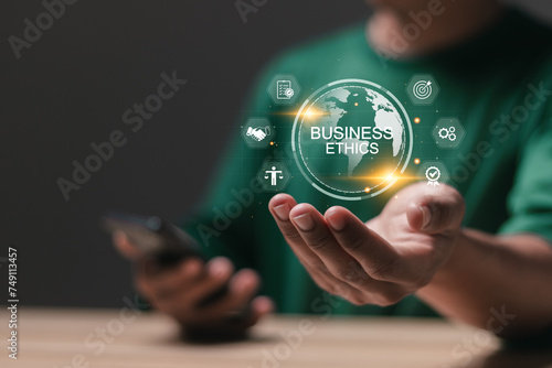 Business ethics concept. Code of ethics, moral principles, business integrity, governance policy. Person holding globe with business ethics icon on virtual screen.