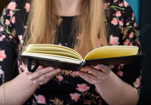 Kobieta trzyma w dłoniach otwartą książkę, czyta
