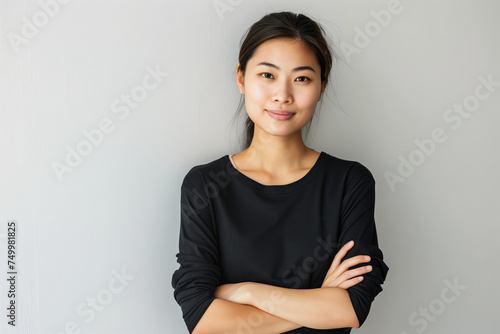 Confident Asian Businesswoman in Casual Black Attire with Arms Crossed on a Simple Background