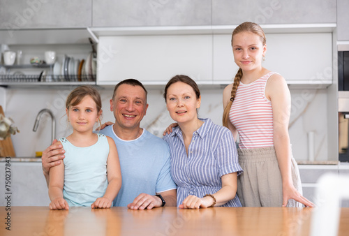Portrait of happy family - father and mother with two children at the table at home