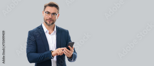 Man in suit using mobile phone isolated on studio background. Portrait of confidence middle aged millennial man using cellphone. Guy with smartphone isolated studio background. Banner, copy space.