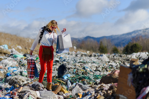 Modern woman on landfill with shopping bags. consumerism versus pollution concept.