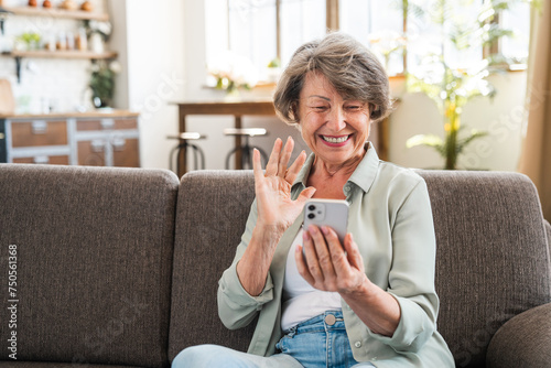 Happy caucasian senior grandmother using cellphone for vlogging blogging. Old woman having videocall selfie online on cellphone at home