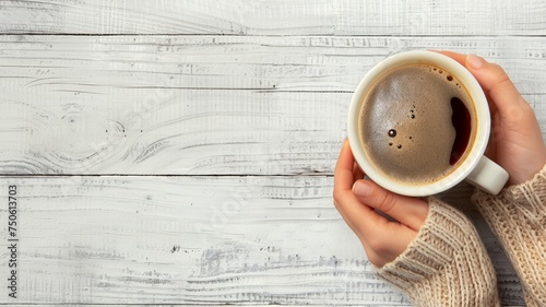 Hand of a girl holding a coffee cup, on a light wooden background, top view, free space