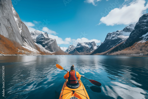 Paddler in an orange kayak journeys through a serene mountainous landscape reflected in calm waters