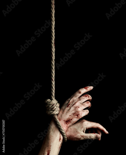 Woman hands with bloody stains tied with a rope over black background. Hostage